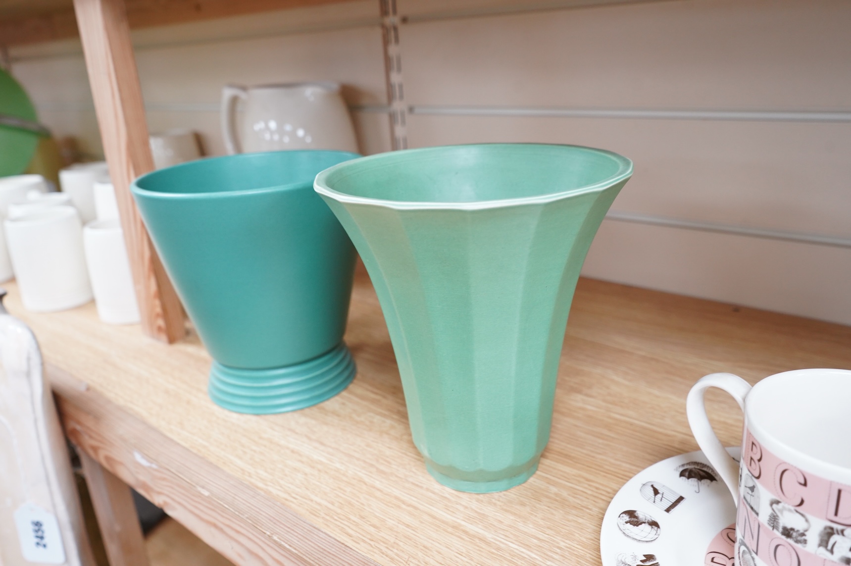 Keith Murray for Wedgwood, two green vases comprising a tapering, fluted example and one with stepped foot, largest 18cm high